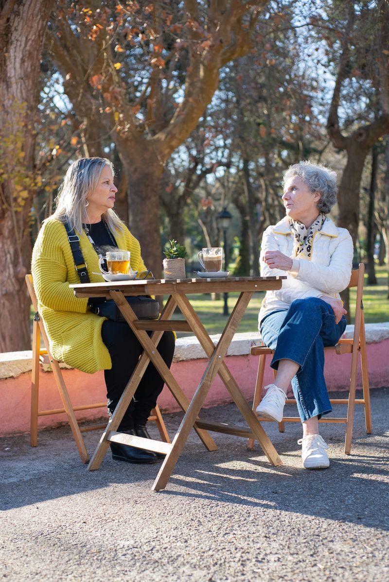 Two senior women talking together at an outdoor café table